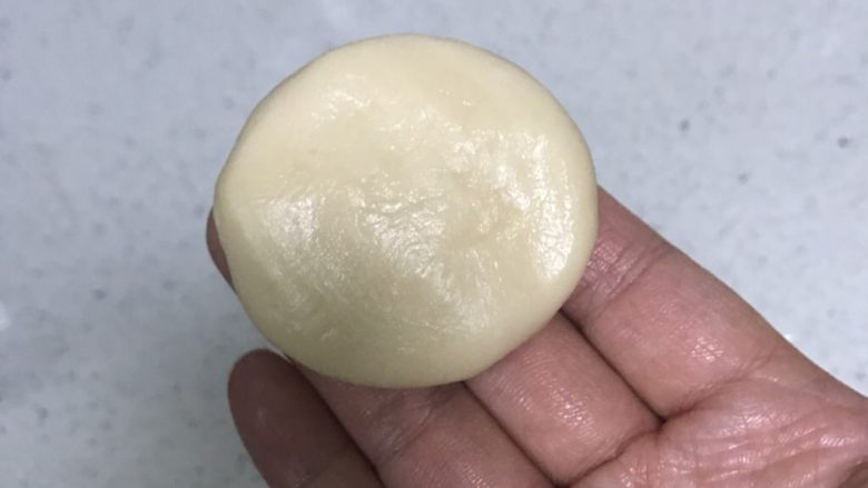 蛋黄酥,用手把包住油酥的面团压扁,进行第一次擀卷。