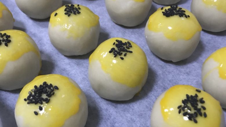 蛋黄酥,都包好后,烤箱上下火180度预热,蛋黄酥刷上蛋黄液,撒上黑芝麻。