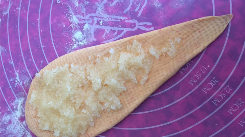 胡萝卜椰蓉卷儿小餐包,将椰蓉在面皮上铺均匀,注意底端尖角那里不要铺了。