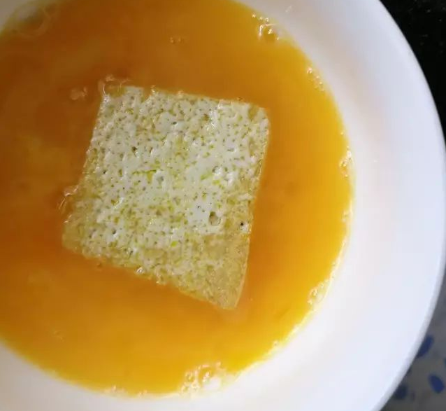 黄金豆腐烩,沥油后的豆腐,在搅拌均匀的蛋液中裹满,再回油锅煎至金黄
