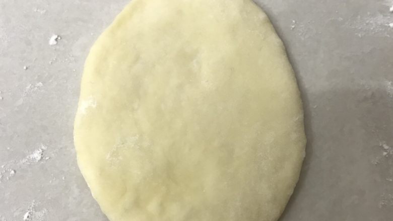 热狗面包,取一个面团,收口压在底下用擀面杖从中间向两头擀成长舌形