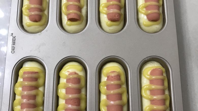 热狗面包,把火腿肠压入面团中,挤上沙拉酱