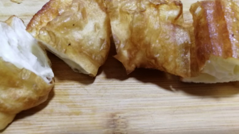油条豆乳抱蛋,油条放在案板上切成小段,