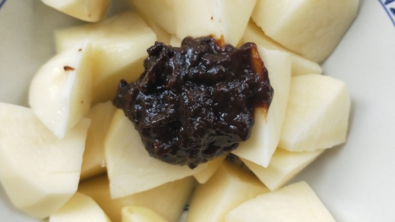 “妈妈牌”粉蒸肉土豆,把沥干水的土豆块放大碗中,加一勺豆瓣酱。