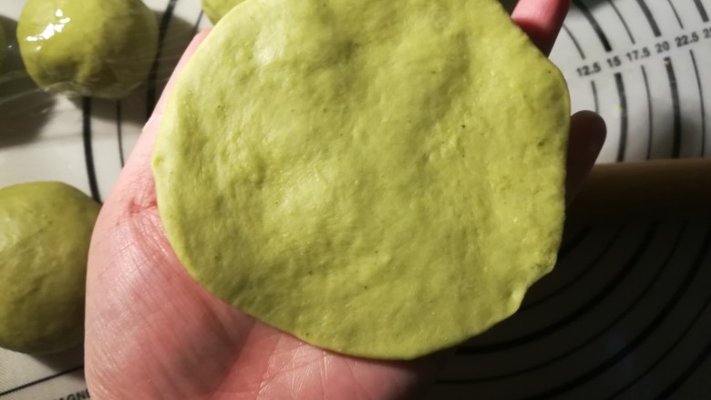 一次发酵的抹茶奶酪包,取一个面团,擀成面饼。