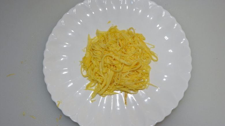 圣诞花环沙拉盘,找一个盘子。将蛋饼丝摆在中心处。