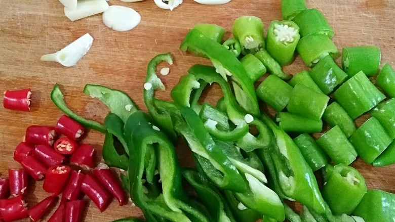 农家小炒肉,辣椒洗净,牛角辣椒切丝,杭椒和小米辣切小段,蒜切片备用。
