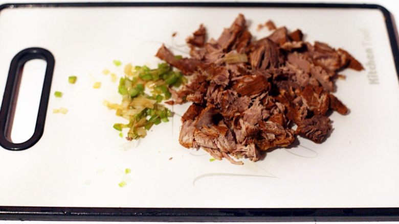 陕西小吃—肉夹馍,将酱好的牛肉切小块,将配菜青椒、青蒜切小丁混合后倒入一些酱牛肉的汤搅匀馅料。