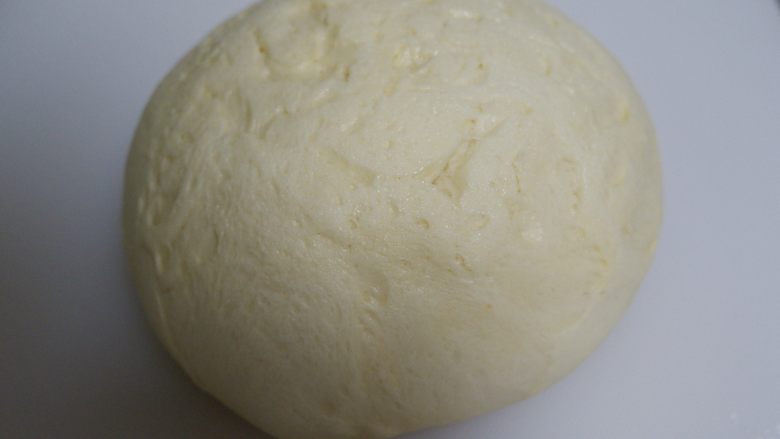 炼乳毛毛虫面包,发酵好的面团取出按压排气,边缘的大气泡拍掉。