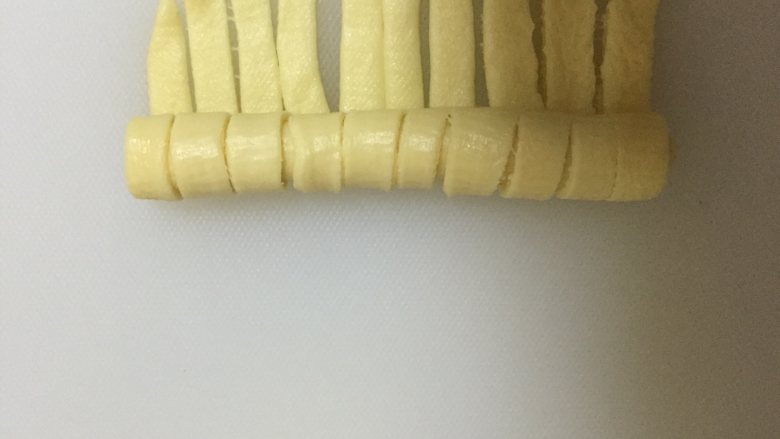 炼乳毛毛虫面包,从没有切口的一头开始卷起来,收口向下放入烤盘进行2次发酵,发酵至1.5倍即可。
