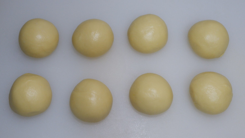 炼乳毛毛虫面包,平均分成8份,滚圆,盖上保鲜膜松弛10分钟。