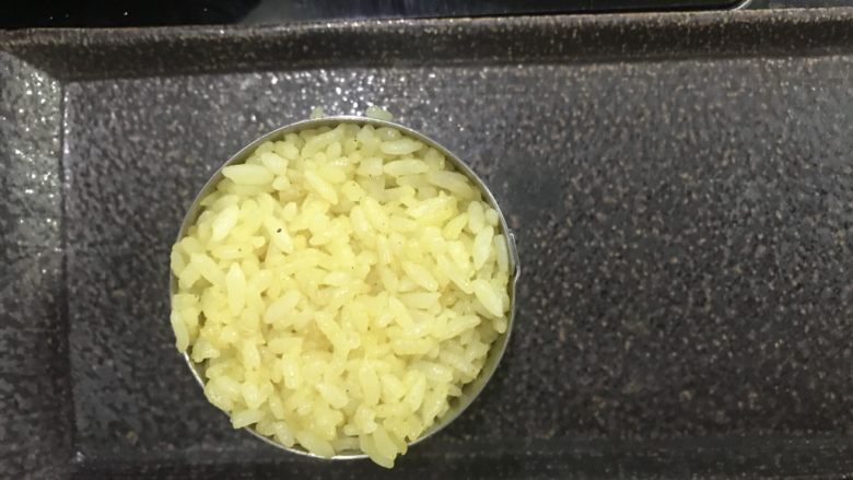 咖喱饭团,把饭填入慕斯圈内,用勺子压紧,拿掉慕斯圈