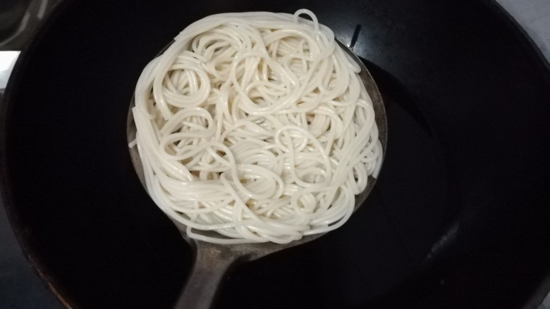 鸟巢豆腐丸子沙拉,将面条捞出,盘在漏勺里面。我