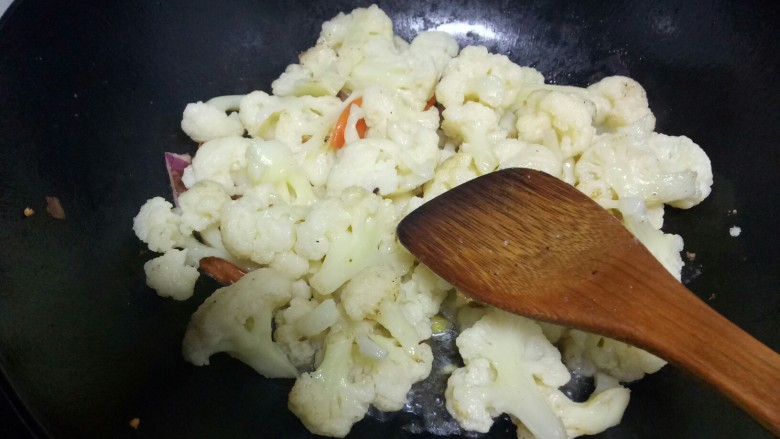 菜花炒肉,锅中放入适量油,放入一半的洋葱丝和蒜瓣,放入菜花和胡萝卜片。