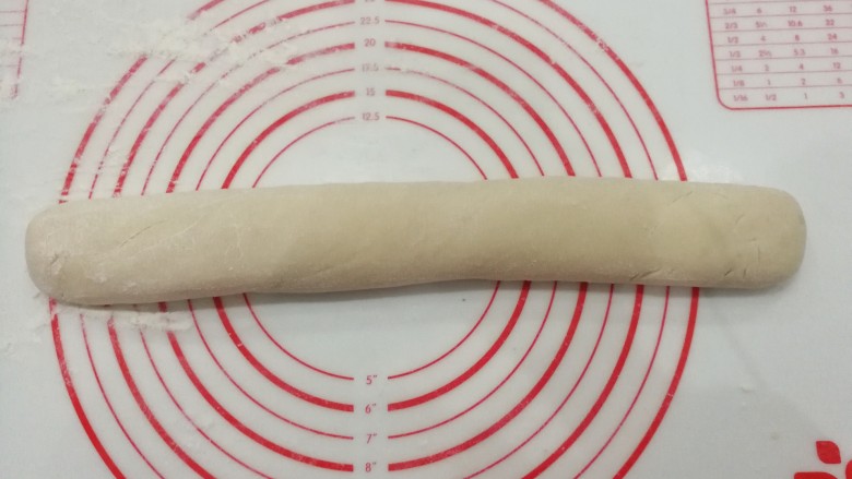 自制健康小油条,揉面垫洒点手粉,把面团滚成圆条状;