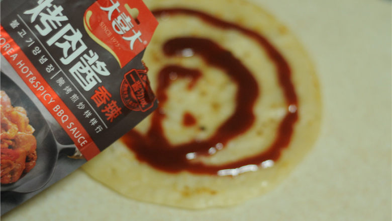 烤肉酱香饼,煎好的饼出锅,淋上少许烤肉酱,刷匀