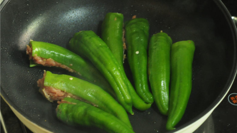 青椒酿肉,锅烧热,倒入少许油,烧热后将青椒摆在平底锅里煎,将有肉的一面朝下,小火慢煎