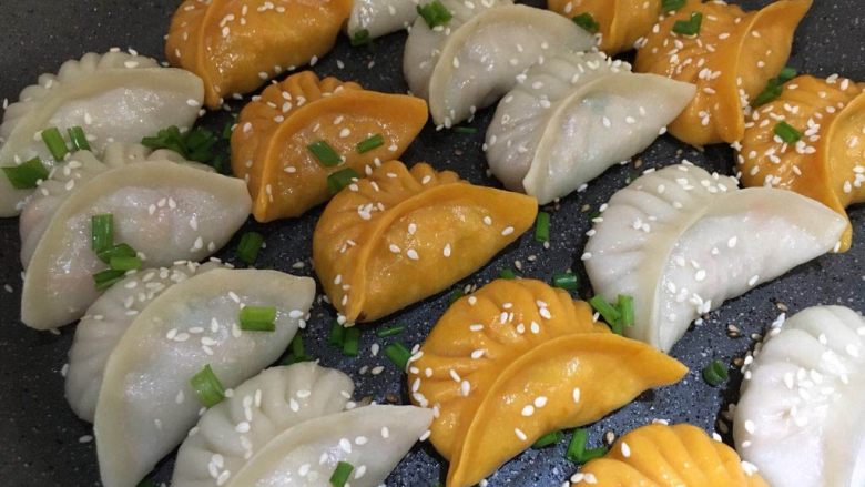 双色煎饺,等水分全部蒸发,再加一点油,让底部变脆,表面撒上葱花芝麻