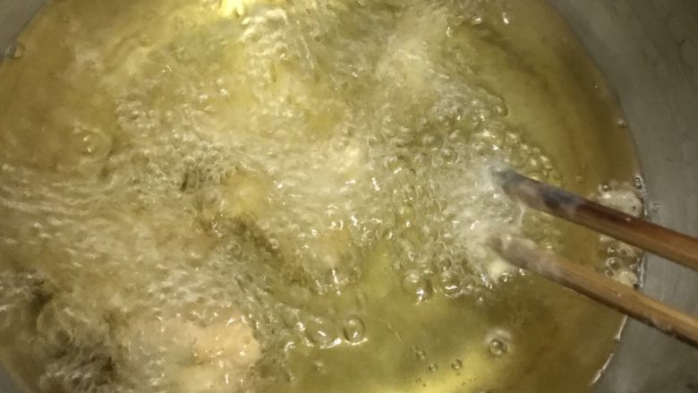 菠萝咕咾肉,用筷子快速把挂浆的肉块放入热油中,一块块放,不能全部倒进去,会全部粘成肉饼的。