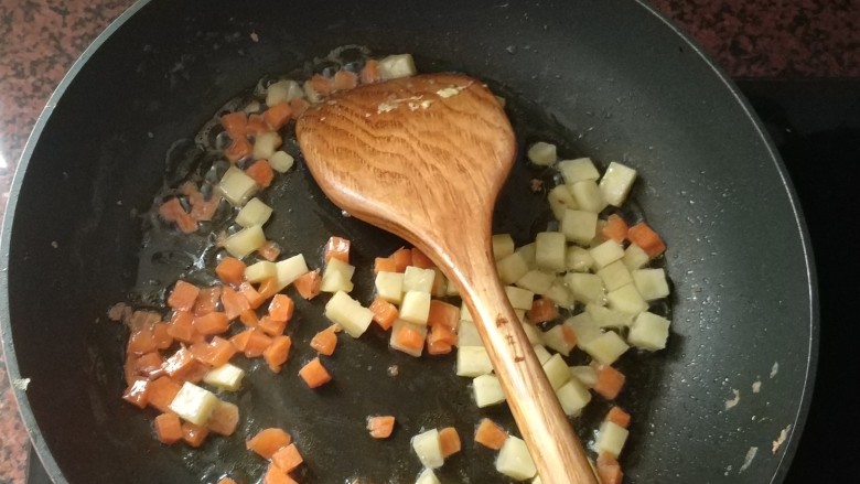 咖喱蛋炒饭,平底锅热油,倒入胡萝卜丁、土豆丁翻炒