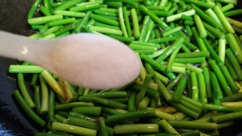 蛋裹肉碎炒蒜薹,煸炒一会儿后倒入一小勺盐。再翻炒几下,