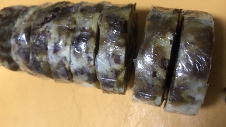 老北京清真小吃-糖卷果,将冷藏好的卷果取出,为保证好切块,不要立刻将保鲜膜揭下,要带着保鲜膜切成一公分厚的块。