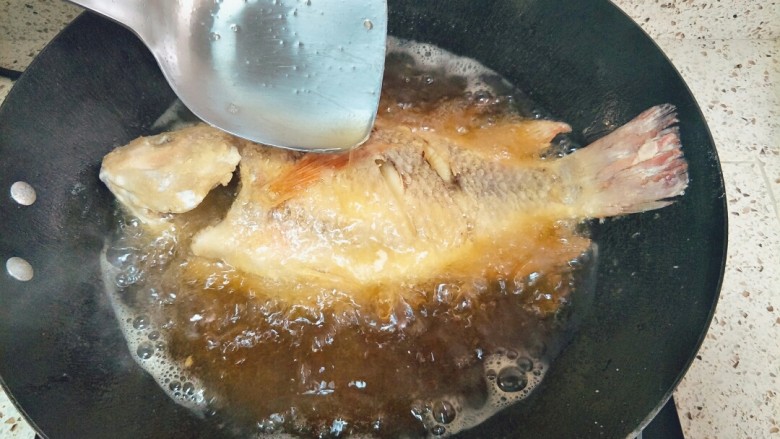 家常糖醋鱼,一面炸定型翻面,一边炸一边往鱼身上浇油