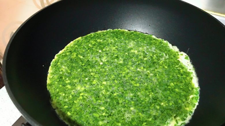 春游食谱~韭菜煎蛋,晃动锅子,让蛋液均匀铺在锅底。