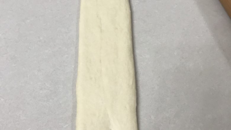 70%蜂蜜蛋白吐司,再调转方向用擀面杖从中间向两头擀开,擀成长方形,宽窄不一样的地方用手整理一下,大约30厘米长,宽7厘米,靠近自己的一面用手指压扁
