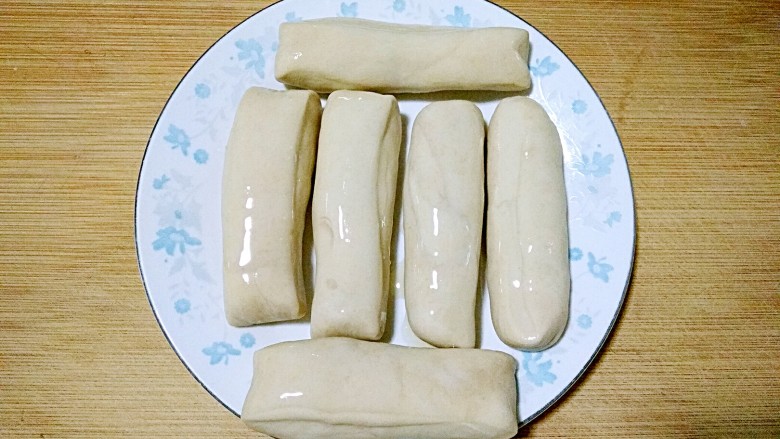 济南名小吃――油旋儿,将切好的面剂搓长条，抹油，盖保鲜膜再醒15-20分钟。