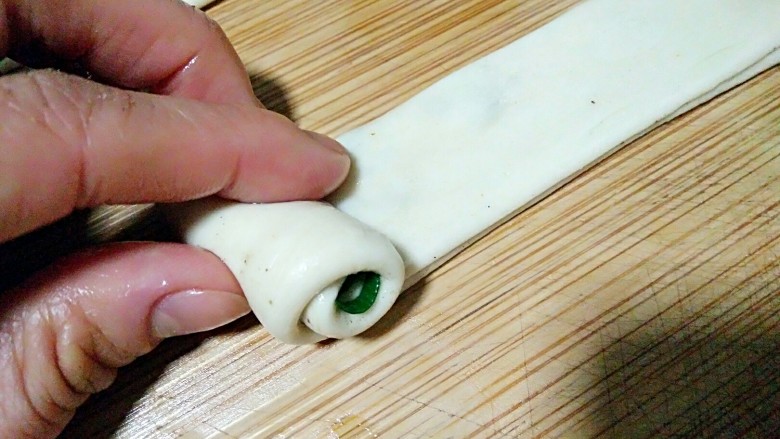 济南名小吃――油旋儿,将抻好的长条从一边卷起。
