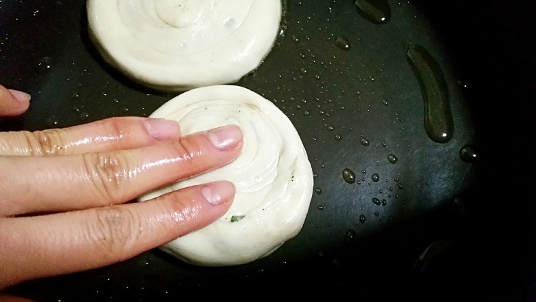 济南名小吃――油旋儿,用手将面剂稍微向周围按扁。