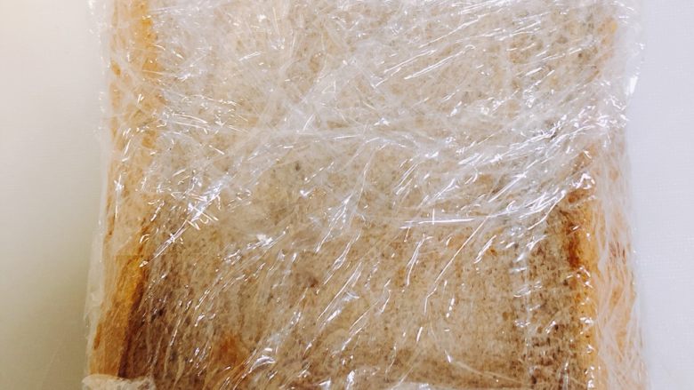 全麦三明治,这时候关键的一步来了，用垫在下面的保鲜膜把做好的三明治包裹好，压压紧