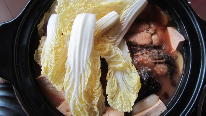 砂锅鱼炖豆腐,剩余时间10分钟时加入娃娃菜,尝一下味道,如果不咸可以加入适量盐,加盖炖煮至结束