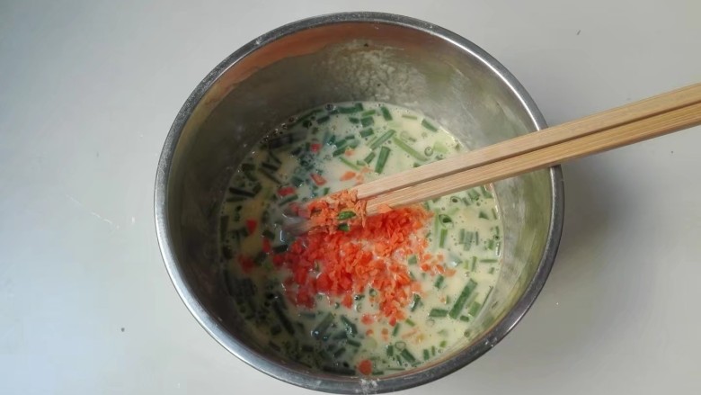 摊香葱萝卜末鸡蛋饼,放入葱胡萝卜末拌匀