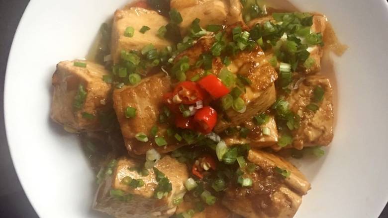 可乐烧豆腐,装盘,撒上葱花和红椒圈点缀即可。