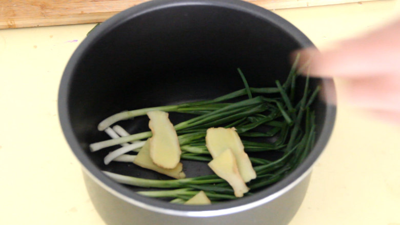 电饭煲焖鸡,电饭锅中铺上小葱和姜片