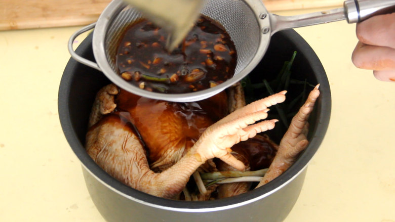 电饭煲焖鸡,把鸡放在上面,然后用滤网滤掉料汁里面的姜蒜末。