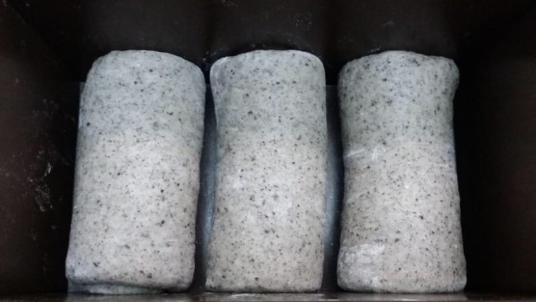 黑芝麻吐司,全部卷好之后,放入土司盒。盖上保鲜膜,放温暖湿润处,进行最后的发酵。发至模具的9分满