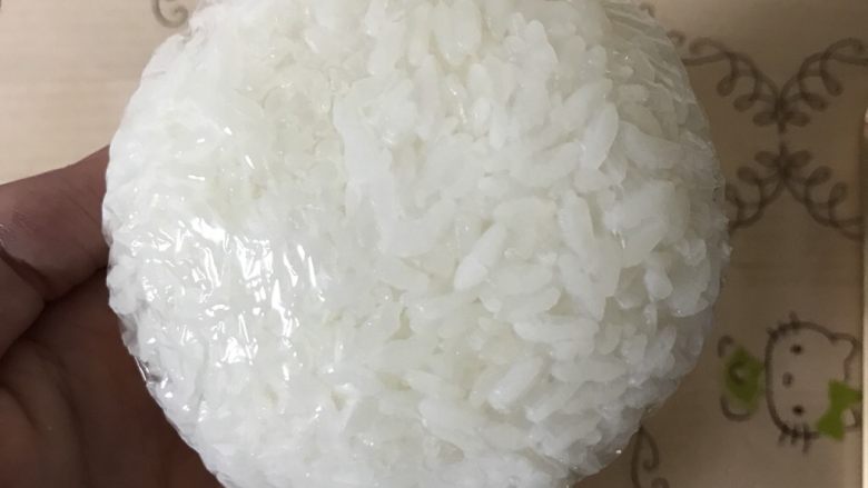 招财猫便当/饭团,取100g米饭,用保鲜膜包裹着捏紧,搓圆,压扁,形成圆形饭团