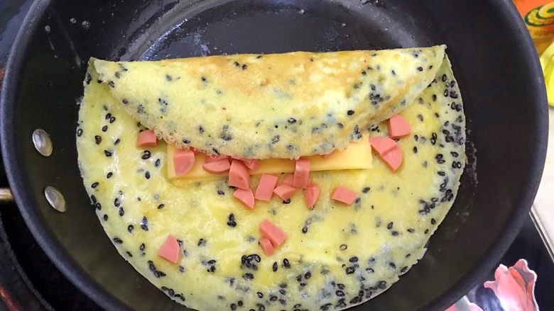做饼~黑芝麻火腿肠芝士鸡蛋饼,用手把蛋饼如图所示,折起