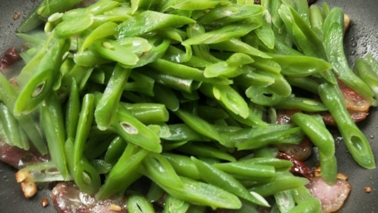 四季豆炒腊肠,倒入四季豆翻炒,让四季豆吸收一点腊肠的油。