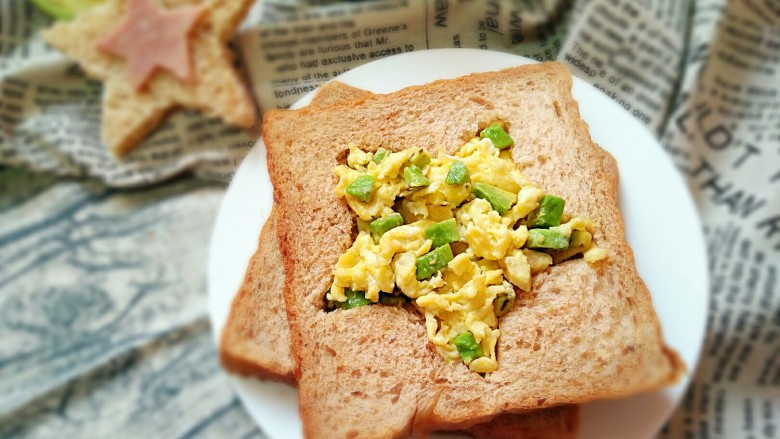 牛油果滑蛋吐司――5分钟快手营养早餐,将炒好的滑蛋牛油果放进吐司刻好的图案中，两片吐司中间再加一片<a style='color:red;display:inline-block;' href='/shicai/ 438'>火腿</a>片即可。