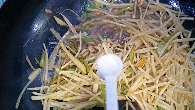 家常土豆丝,翻炒均匀后,倒入一勺盐。