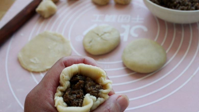 做饼+黄山烧饼,取一个小面剂擀圆（案上和擀面杖上用一点点薄粉），放入馅料约20克包起来。
捏合处做为底面，轻轻地按扁，整理成圆饼。