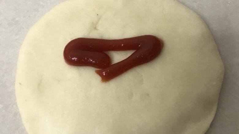 葱香芝士肉松排包,靠近身边的一面,用手指压扁,挤上番茄酱沙司