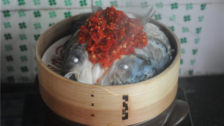 剁椒鱼头,将剁椒均匀地铺在鱼头上,再撒上姜末蒜末,大火蒸制7分钟后出锅