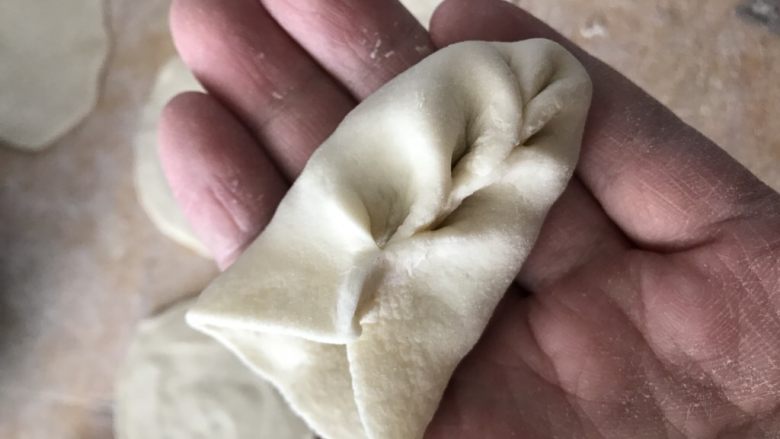 麦穗芹菜馅肉水饺,放上馅,在饺子皮的一端左右捏褶