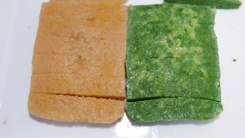 宝宝辅食—双色蔬菜鸡蛋糕,将两块蛋糕贴在一起,切成宽窄相同的条。