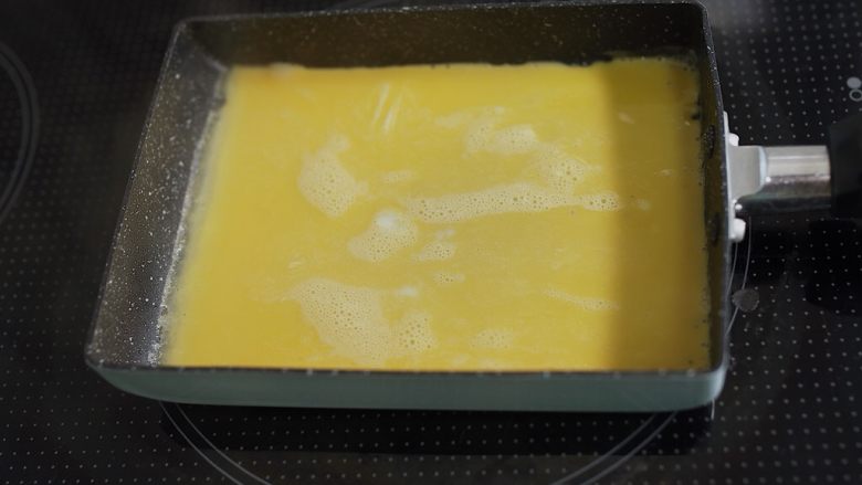 饭团便当,热锅入油(硬币大小吧)用厨房纸抹匀,先倒进去一层蛋液,烙熟之后由把手这边开始卷,卷成卷。